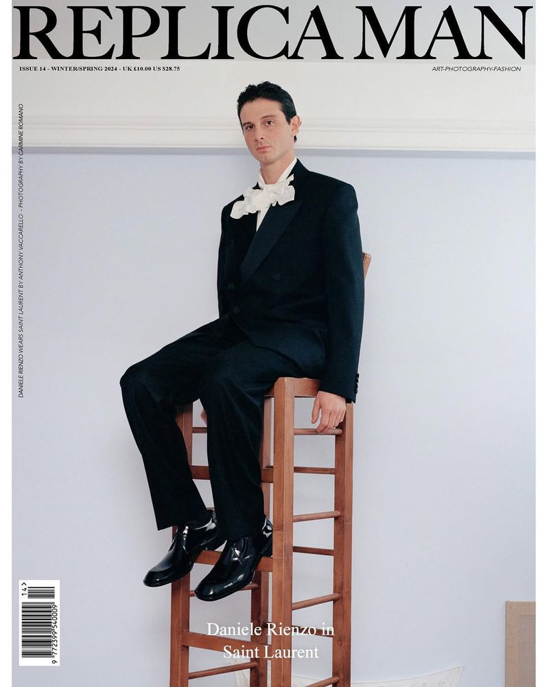 Magazine cover featuring a man in a black suit and white bow sitting atop a wooden ladder against a light wall.