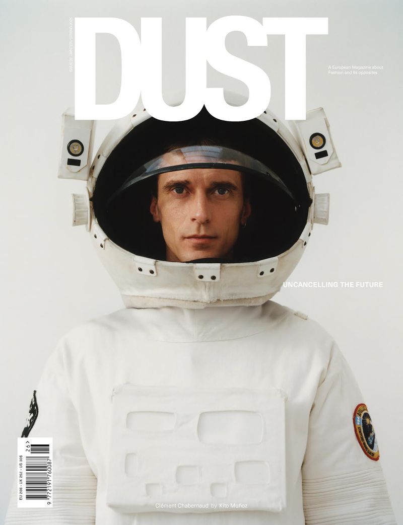 Magazine cover featuring a person in a white spacesuit, head and shoulders, centered, with the word 'DUST' in large white letters.