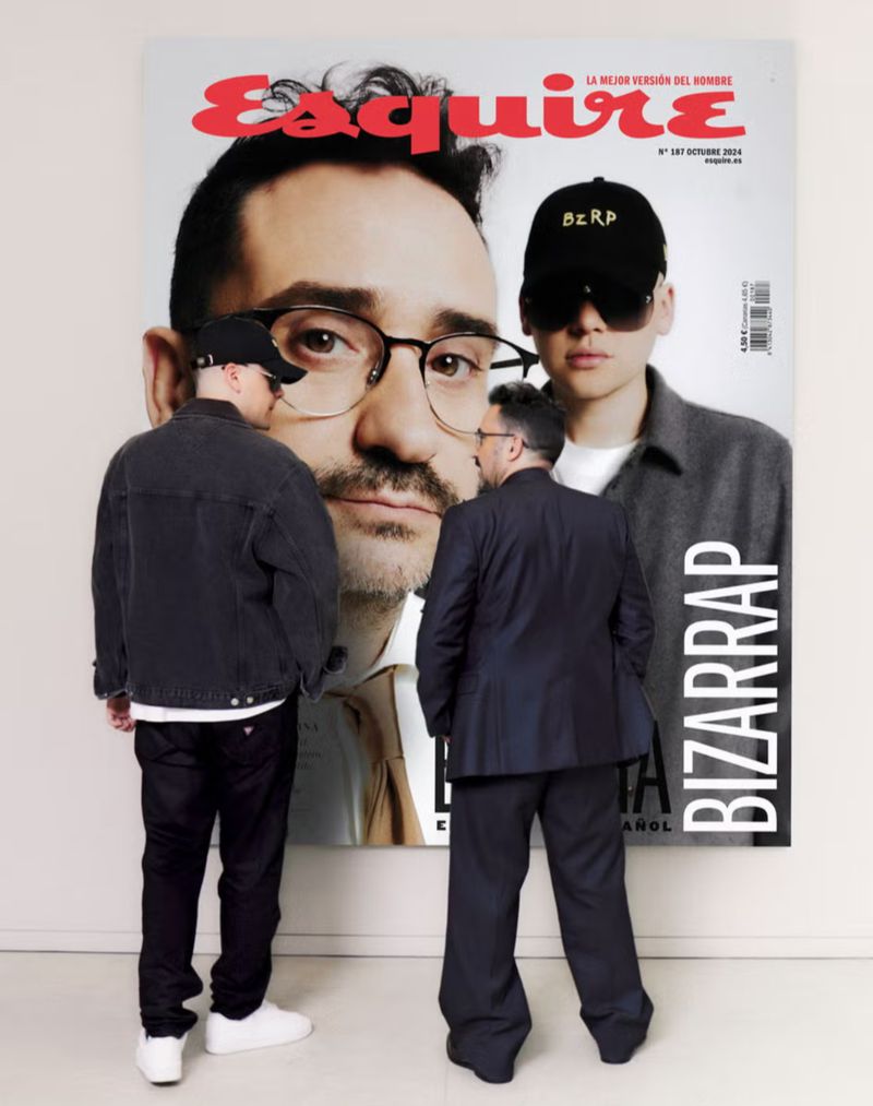 Two men standing in front of a large Esquire Spain magazine cover featuring a portrait of Bizarrap and another man.
