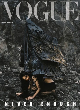 Vogue cover features a model in dark fashion kneeling on rocky ground, under a textured dark structure, against a rocky backdrop.