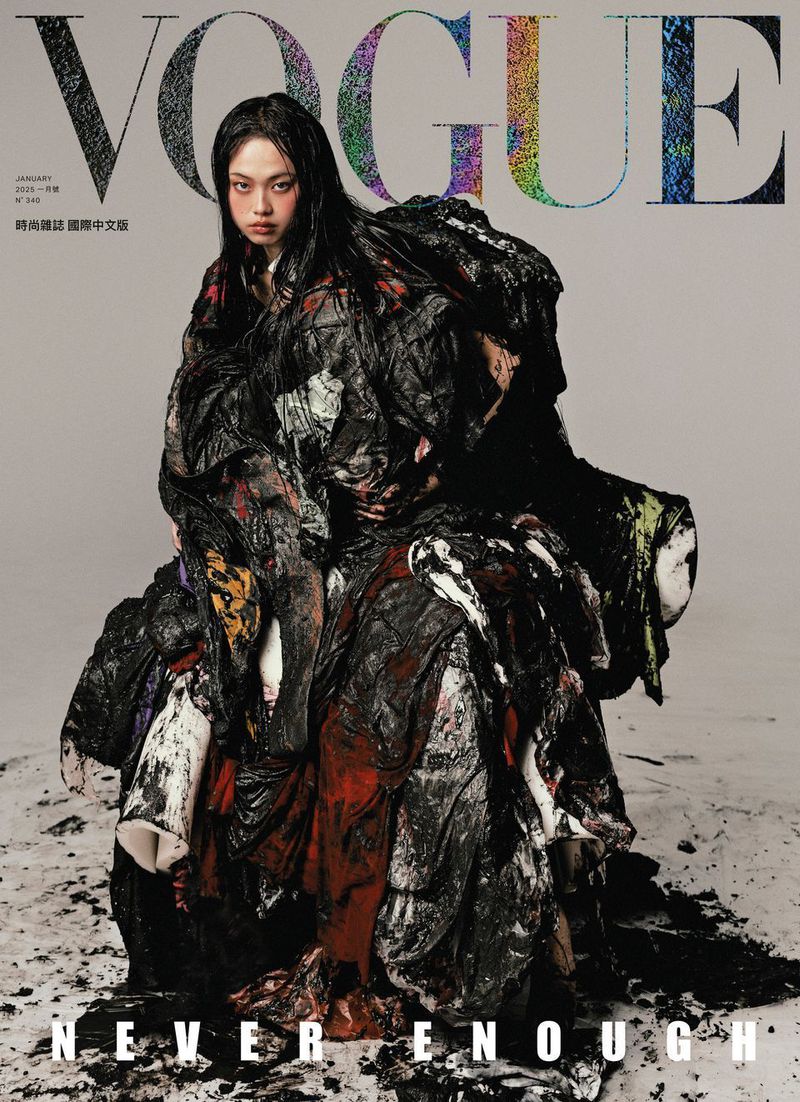 Vogue cover featuring a fashion model with dark hair wearing a large draped garment with dark tones against a neutral background.