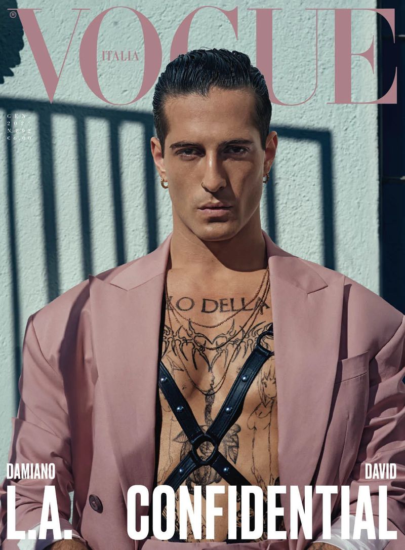 Vogue Italia cover featuring a man with dark hair and tattoos, wearing a pink suit jacket, against a light-colored wall with shadows.