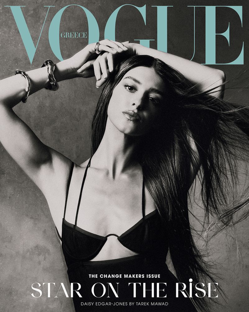 Black and white fashion magazine cover featuring Daisy Edgar-Jones with her hands above her head, jewelry, and dark hair.