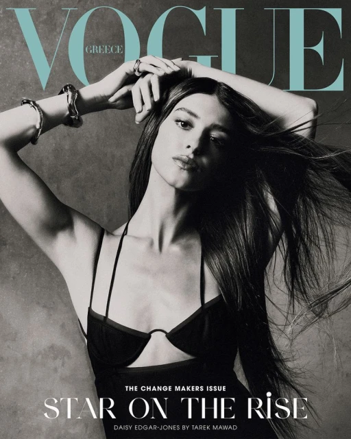 Black and white fashion magazine cover featuring Daisy Edgar-Jones with her hands above her head, jewelry, and dark hair.