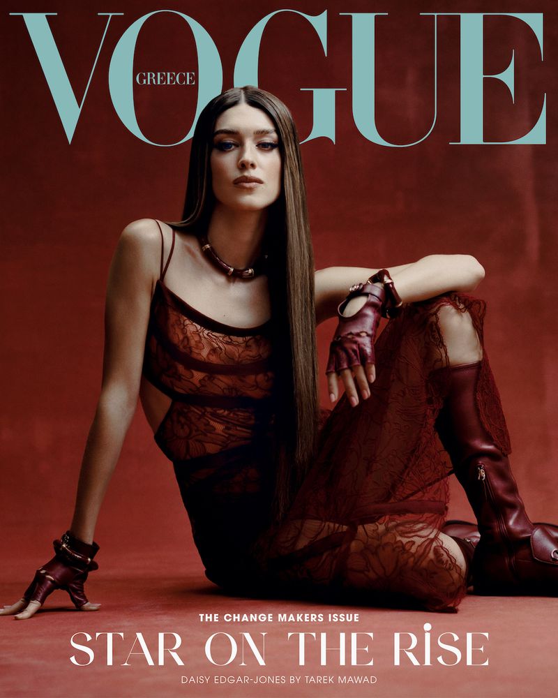 Fashion magazine cover featuring Daisy Edgar-Jones with long brown hair, wearing a maroon dress and gloves against a maroon background.