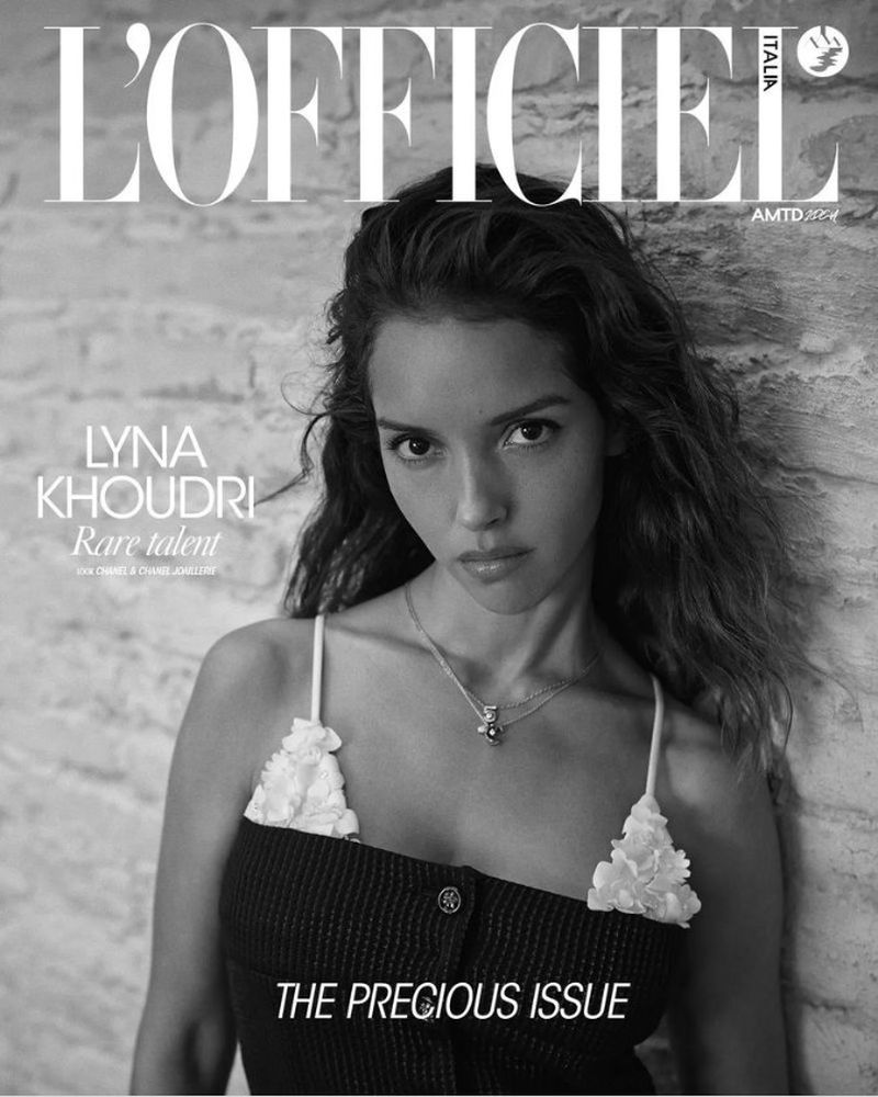 Black-and-white fashion magazine cover featuring Lyna Khoudri in textured top, set against a stone wall with visible magazine text.
