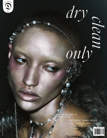 Close-up of a silver-skinned woman with elaborate jewelry and accessories against a dark background, featured on a magazine cover.