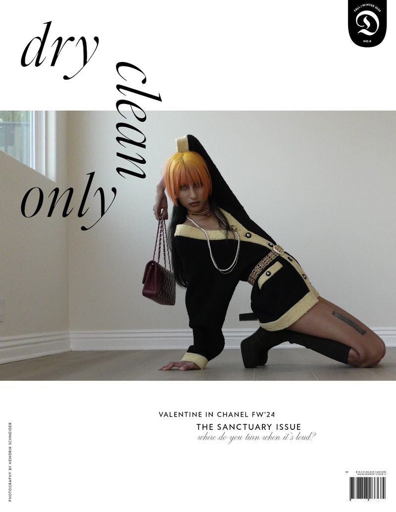 Fashion editorial shot of a woman with orange hair in a black and yellow Chanel outfit, posing on the floor with a burgundy Chanel purse.