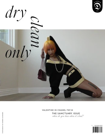 Fashion editorial shot of a woman with orange hair in a black and yellow Chanel outfit, posing on the floor with a burgundy Chanel purse.