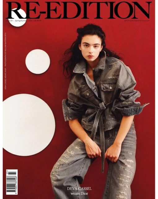 Magazine cover featuring a young woman with long hair wearing a denim outfit, posing in front of a red wall with white circles.