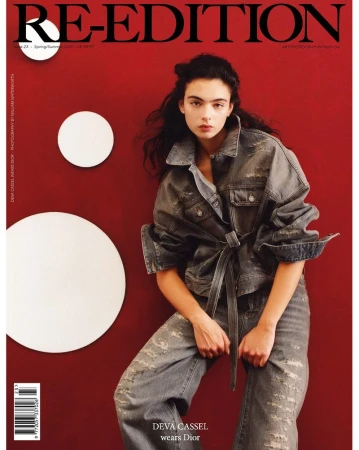 Magazine cover featuring a young woman with long hair wearing a denim outfit, posing in front of a red wall with white circles.