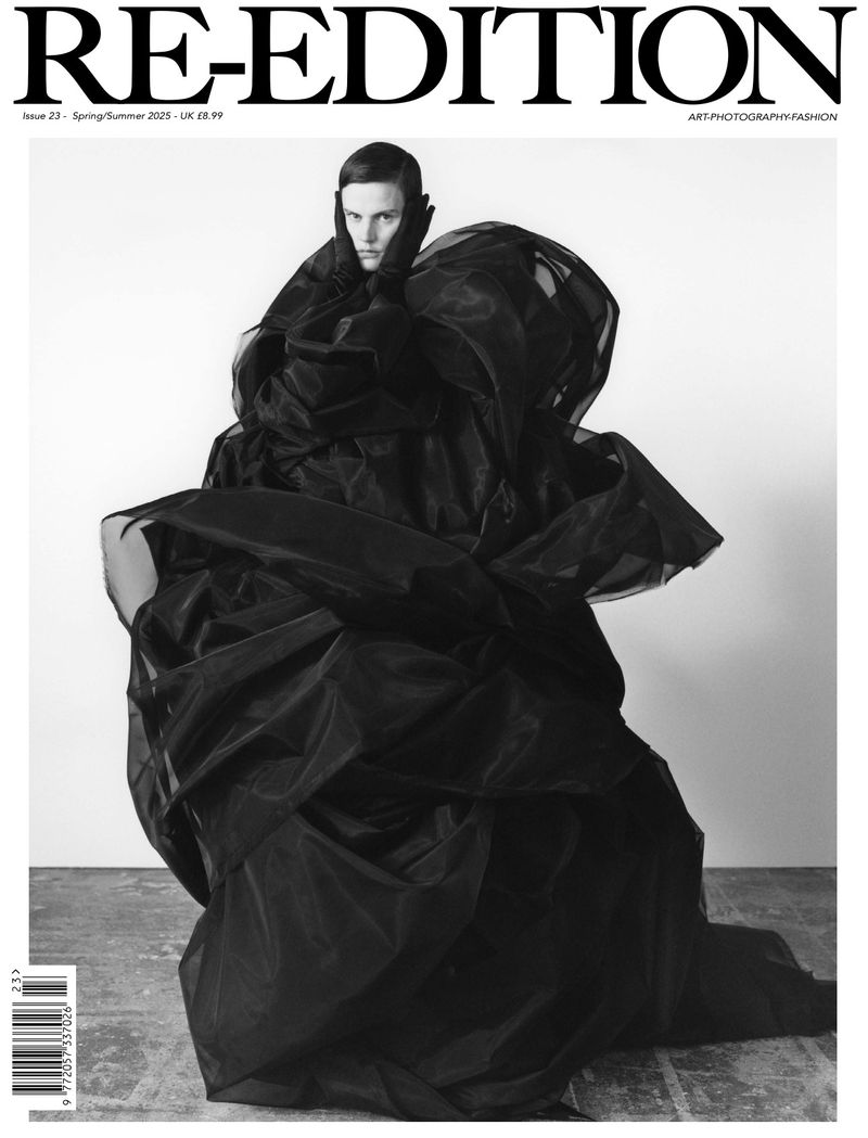 Black and white fashion magazine cover featuring a model in an avant-garde black dress with a dramatic tulle-like texture.