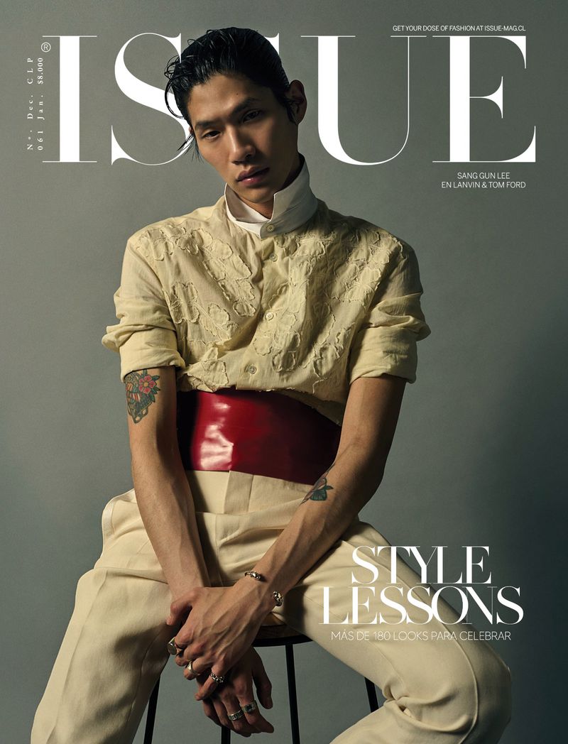 Magazine cover featuring Asian male model Sang Gun Lee wearing a cream-colored, embroidered shirt, red sash, and cream pants while seated on a stool.