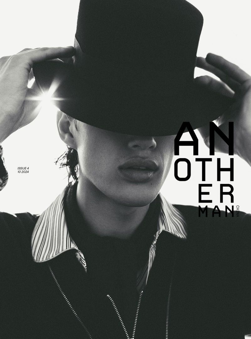 Magazine cover featuring a person with a top hat covering their eyes, wearing a collared zip-up jacket in a black-and-white portrait.