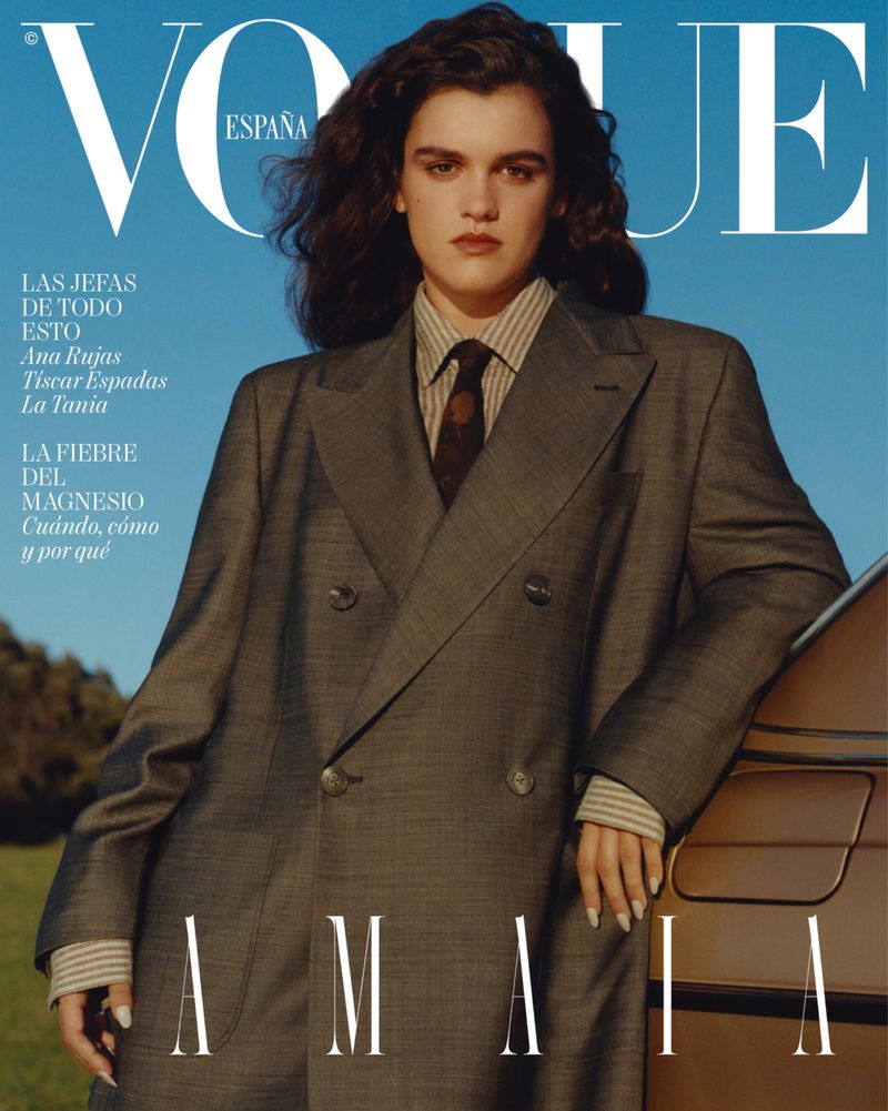 Vogue Espana cover featuring a woman in a grey suit, posing next to a car with a blue sky and grassy field in the background.