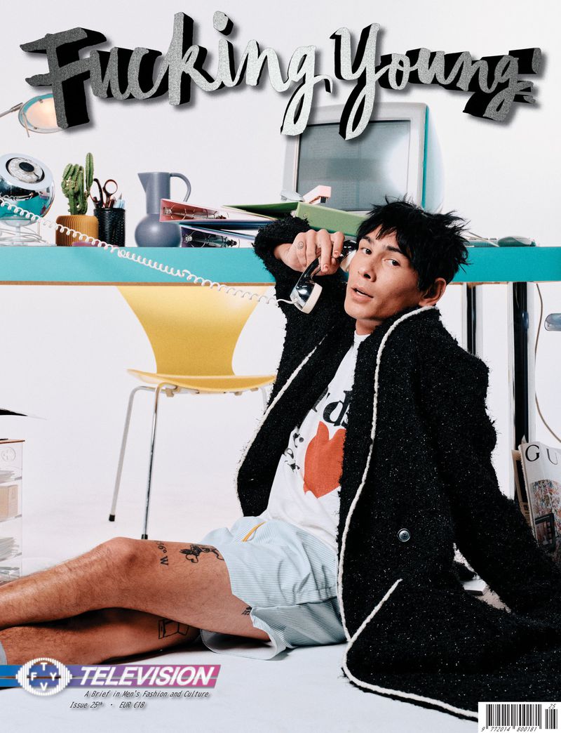 Magazine cover featuring a stylish adult male in a jacket, shorts, and tee shirt holding a vintage phone receiver in an indoor setting.