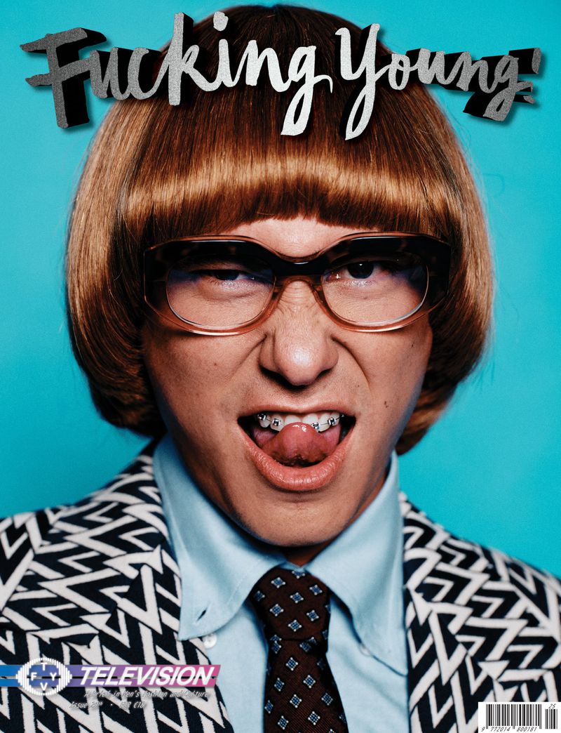 Magazine cover featuring a person with blond bowl cut, braces, and black and white patterned jacket against a blue background.