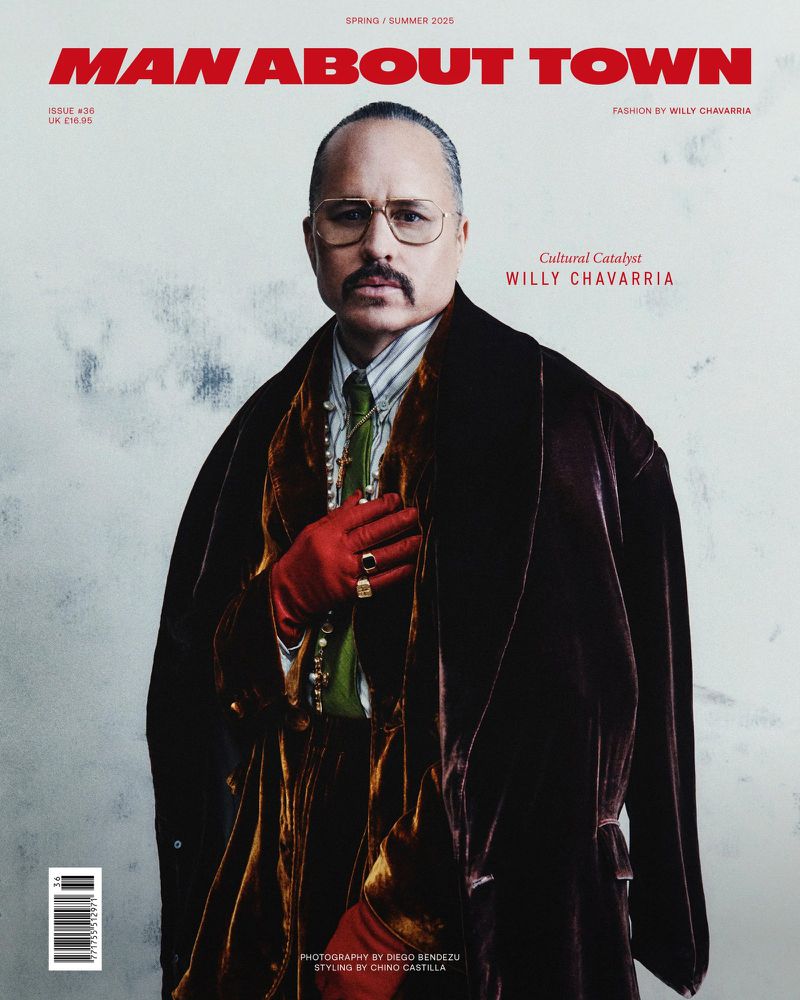 Magazine cover featuring a man in a brown velvet coat and red gloves, wearing glasses, a tie, and jewelry against a mottled white background.