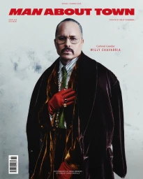 Magazine cover portrait of Willy Chavarria in a dark velvet coat with red gloves and glasses against a textured wall