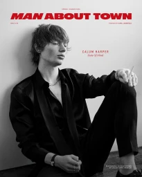 Monochrome magazine cover featuring Calum Harper seated against a plain studio wall wearing a dark shirt