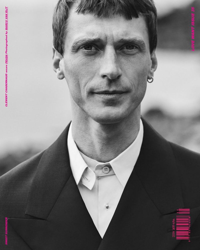 Monochrome portrait of a slender adult male with a dark blazer and light shirt in an outdoor setting, moody and editorial.