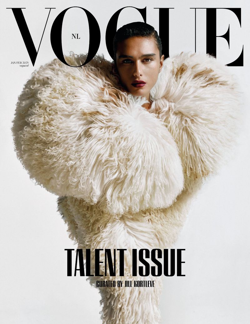 Vogue NL magazine cover featuring a person in a large, textured white coat. The person has dark hair and is centered in the frame.