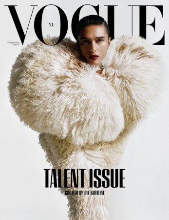 Vogue NL magazine cover featuring a person in a large, textured white coat. The person has dark hair and is centered in the frame.