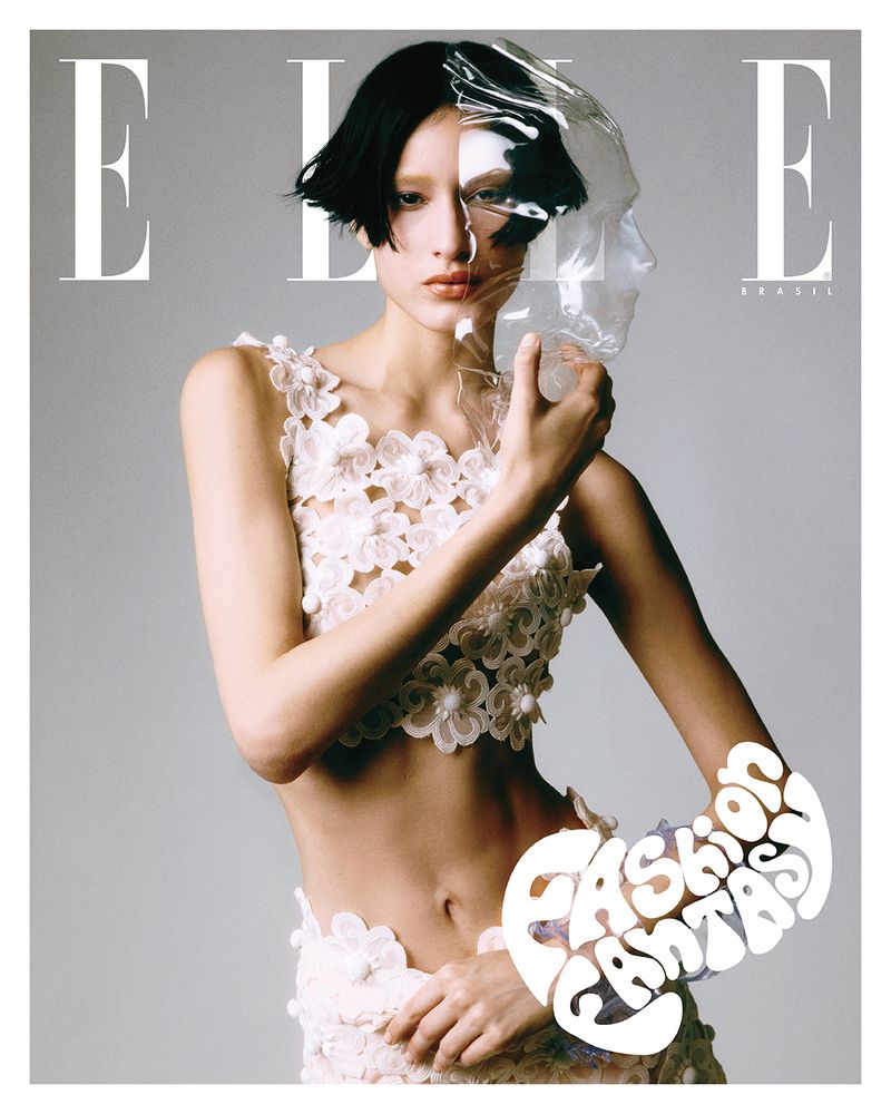 Elle Brasil magazine cover featuring a woman in a floral outfit holding a clear plastic face sculpture against a light gray backdrop.