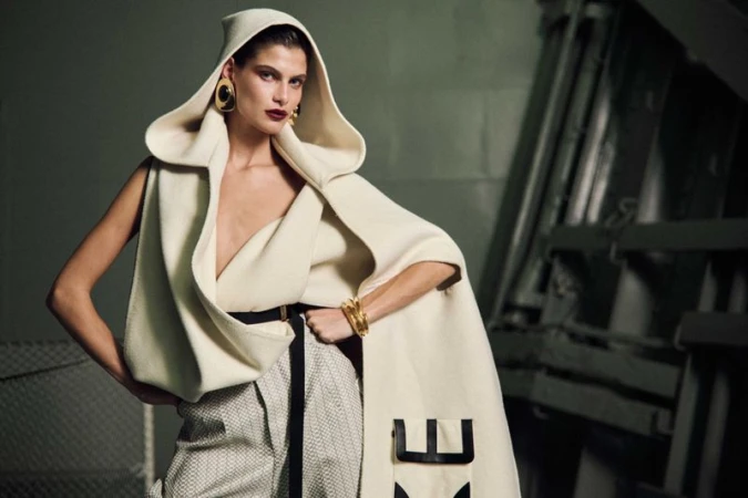 Model Anthi Fakidari wearing a hooded cream wool cape and patterned trousers for Vogue Greece