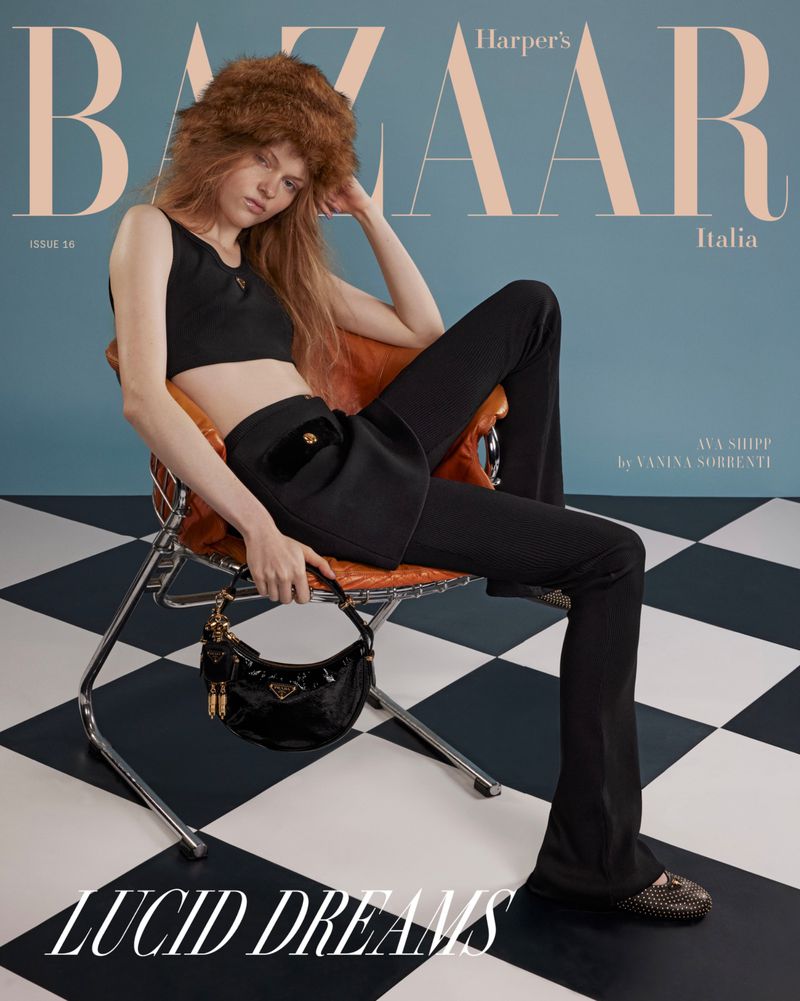 Magazine cover featuring a young woman with long hair and a furry hat, seated in a modern chair with a Prada handbag.