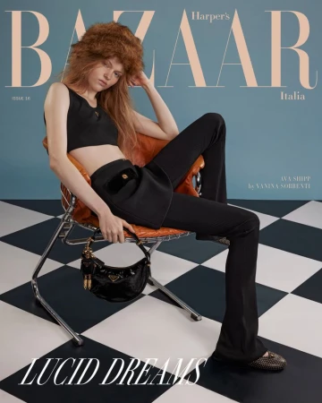 Magazine cover featuring a young woman with long hair and a furry hat, seated in a modern chair with a Prada handbag.