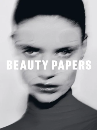 Close-up portrait of a model with motion blur and overlay text reading BEAUTY PAPERS against a white background