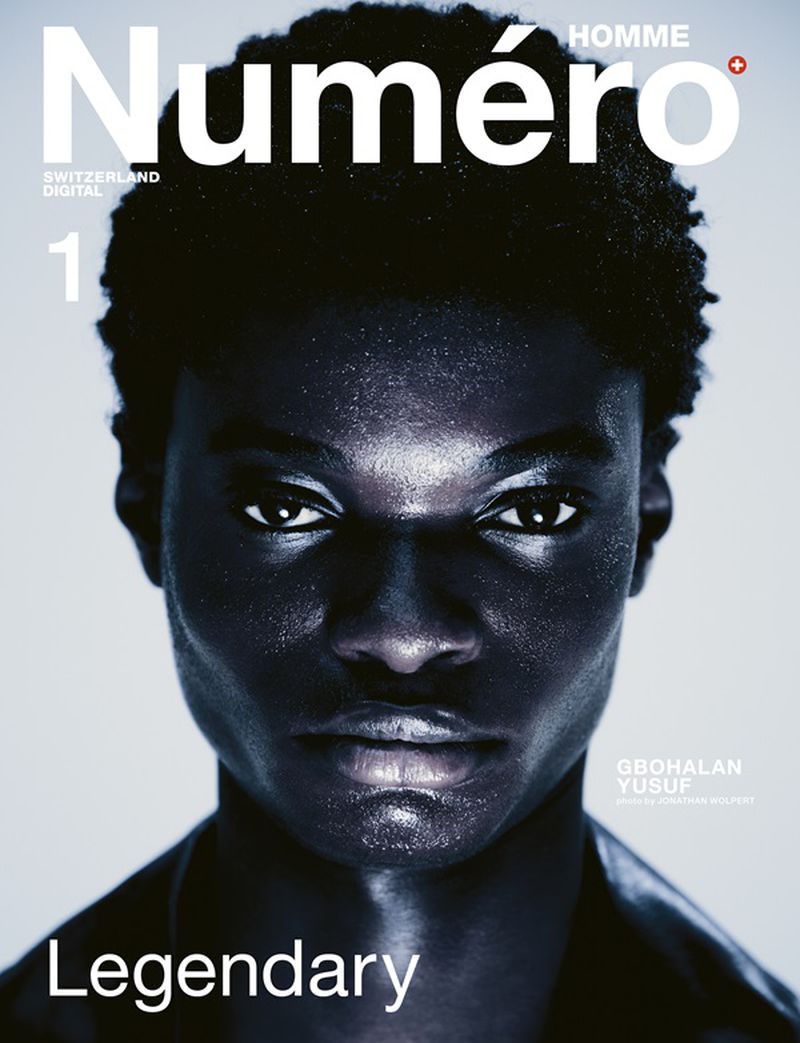 Close-up portrait of model Gbolahan Yusuf for Numéro Homme Switzerland, featuring bold white typography against a clean backdrop.