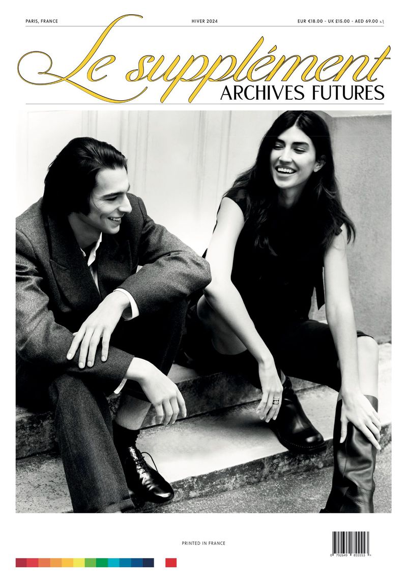 Black and white fashion magazine cover featuring a smiling couple in jackets and boots, leaning against concrete steps with magazine text overlay.