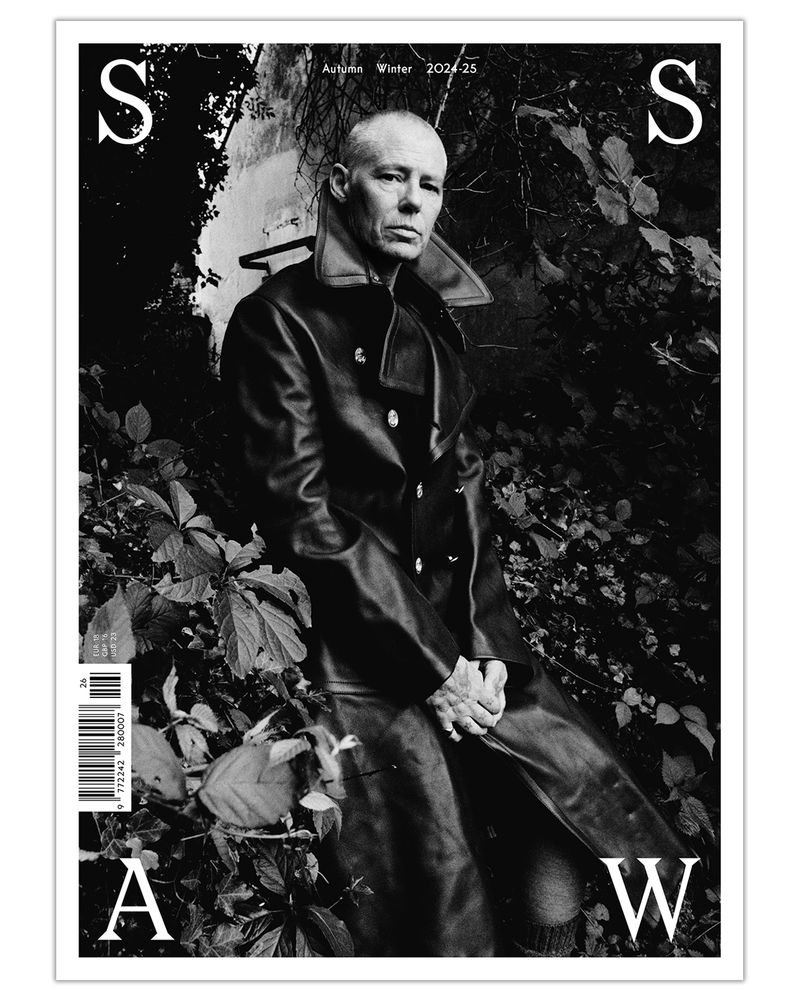 Black-and-white magazine cover features an adult male in a dark coat surrounded by leaves and text, autumn/winter 2024-25.