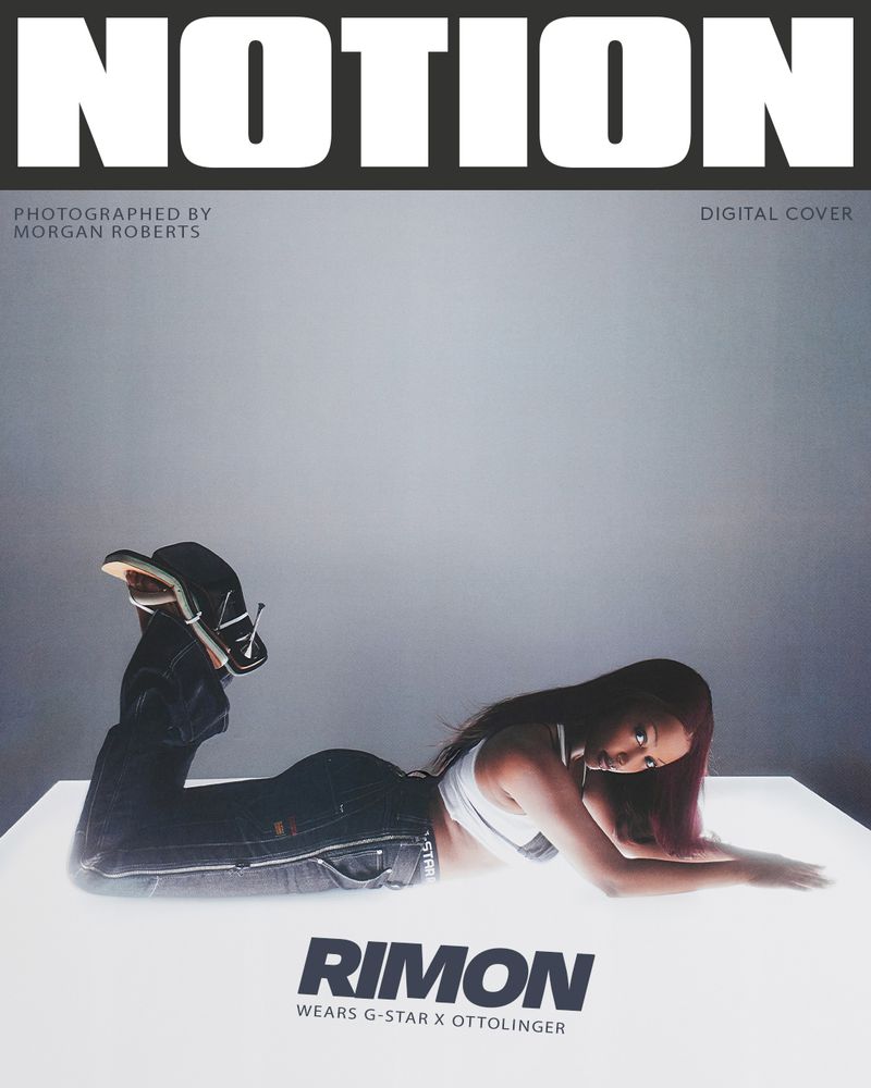 Fashion magazine cover featuring a woman in jeans and a white top lying on a glowing surface with bold text overlays.