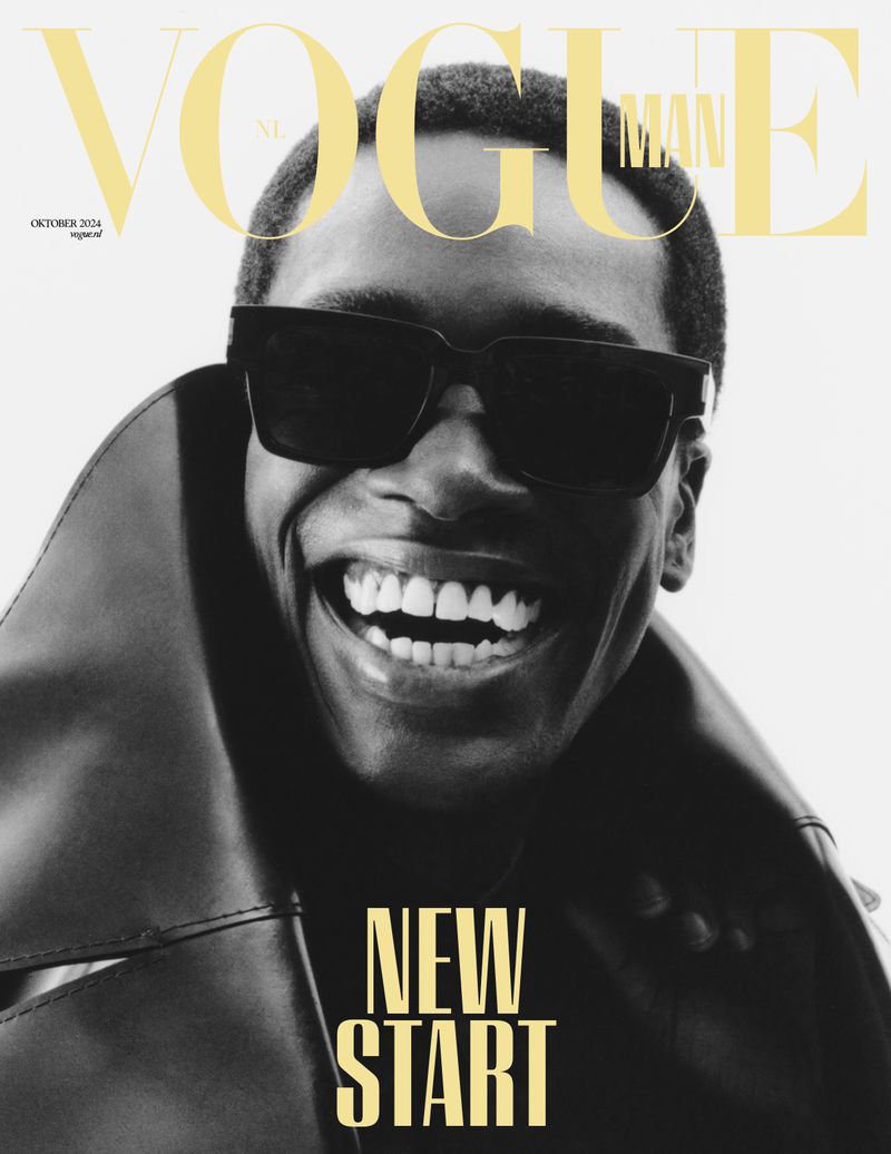 Vogue Man magazine cover featuring a smiling Black male model in a black jacket and sunglasses against a light background.