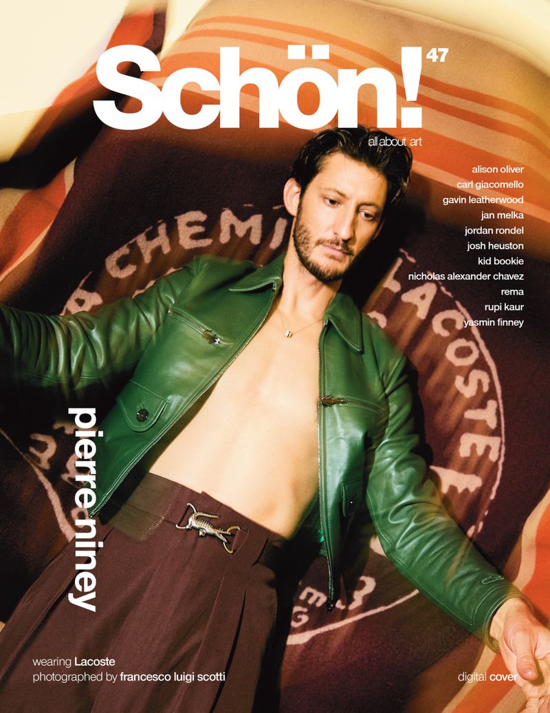 Magazine cover featuring a man in a green leather jacket and brown pants lying on a patterned background, promoting Lacoste and Schön!