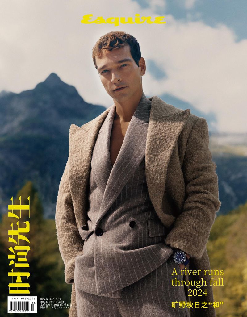 Magazine cover of a male model wearing a tan suit and coat, posing in front of a mountain range with 'Esquire' at the top.