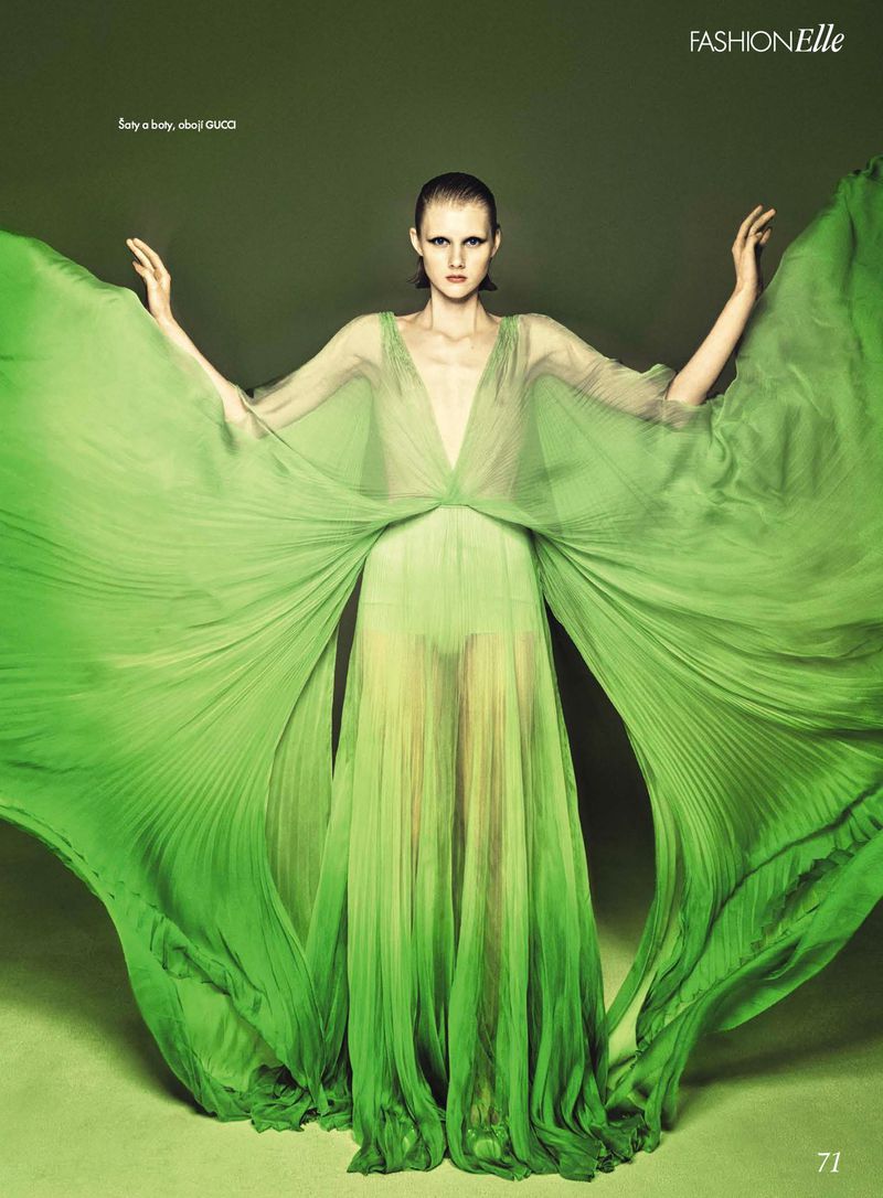 Fashion editorial featuring a woman in a light green, flowing gown with arms raised, set against a green background. Posing for fashion magazine.