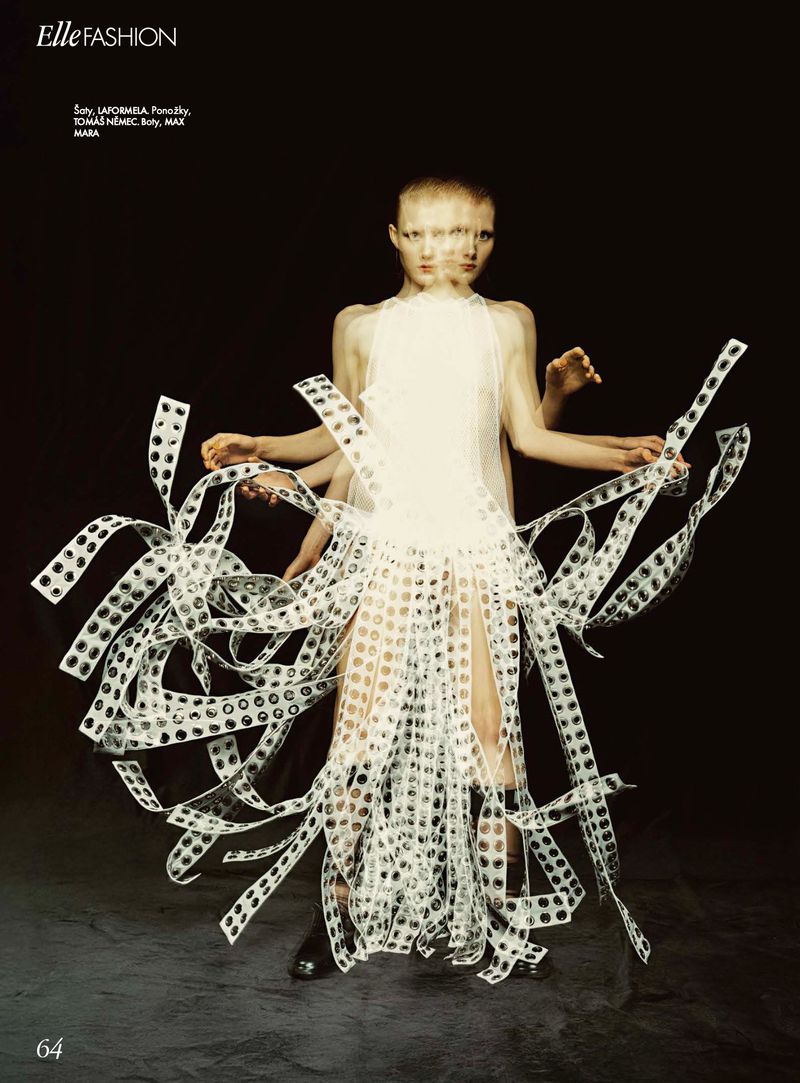 Avant-garde fashion editorial featuring a model in a deconstructed white dress with unique accessories, shot in a dark studio setting.