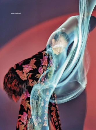 Fashion shot of a woman in an ornate gown with light trails in front of a vibrant red and blue gradient background.