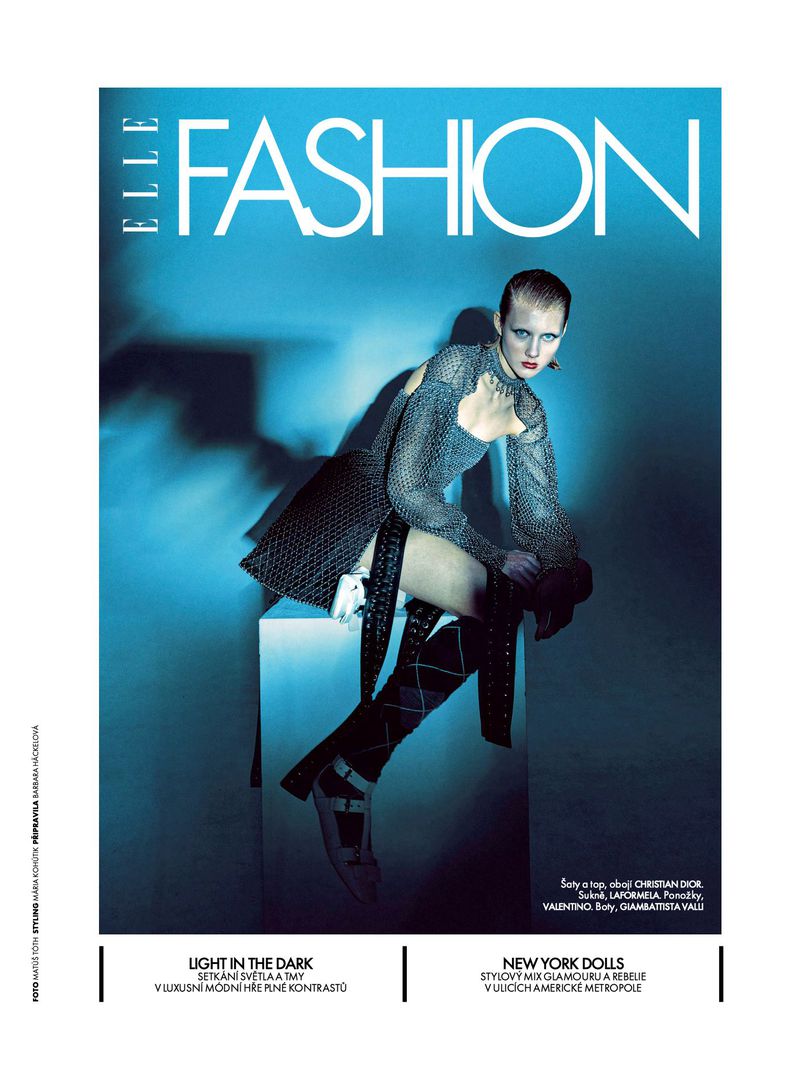 Elle Fashion magazine cover featuring a posed model in a metallic dress and high boots, seated on a cube in a blue-toned studio.
