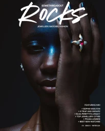 Close-up portrait of a Black woman covering half her face with her hand, wearing an ornate gold ruby ring for a magazine cover.