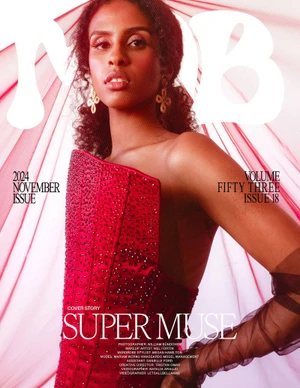 Model wearing a structured red corset top posing in front of sheer pink fabric draped in the background