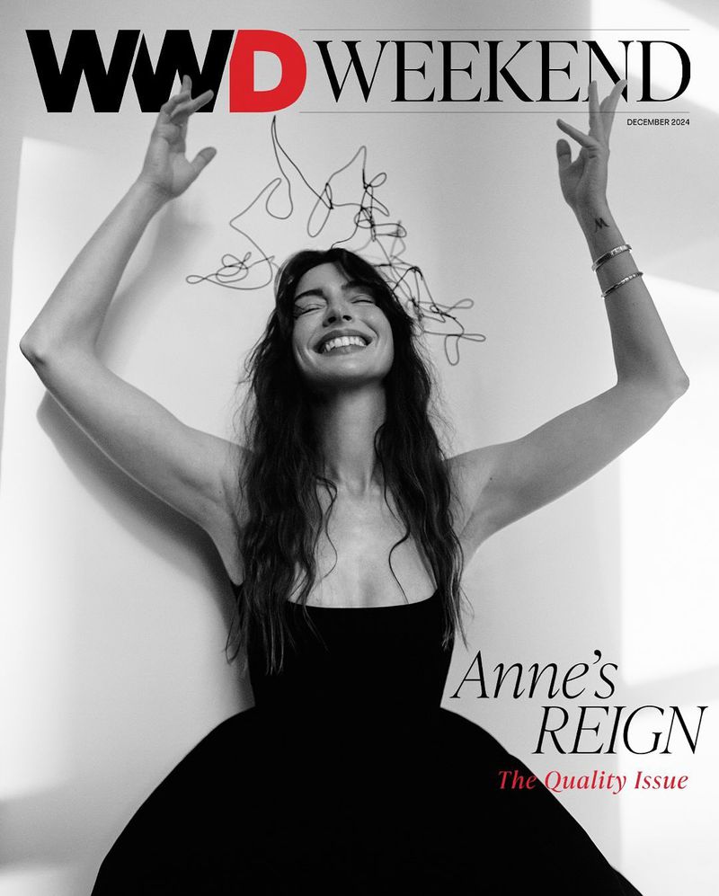 Magazine cover featuring Anne Hathaway in a black dress with her arms raised against a white background and "WWD WEEKEND" masthead.