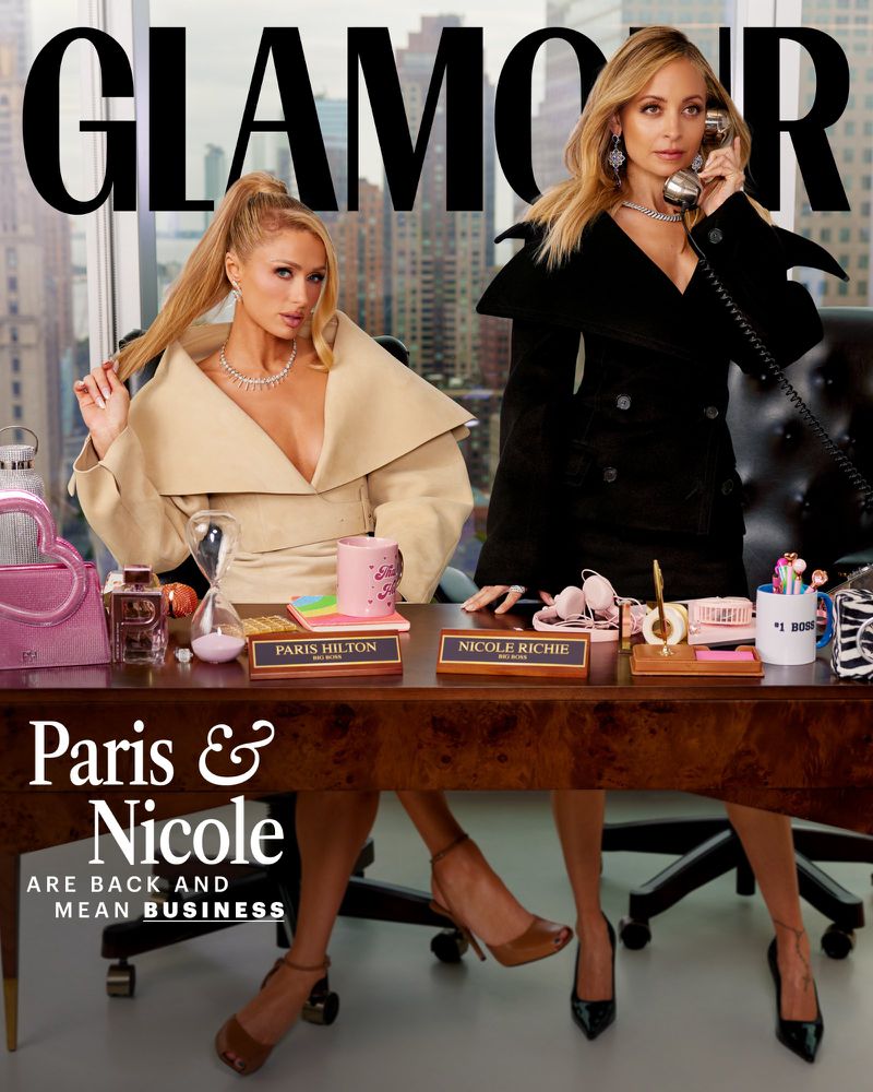 Glamour magazine cover featuring Paris Hilton and Nicole Richie sitting at a desk in front of a city skyline backdrop.