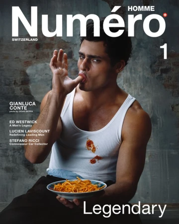Magazine cover featuring a man in a white tank top eating spaghetti, with the 'Numéro Homme Switzerland' masthead and bold 'Legendary' text.