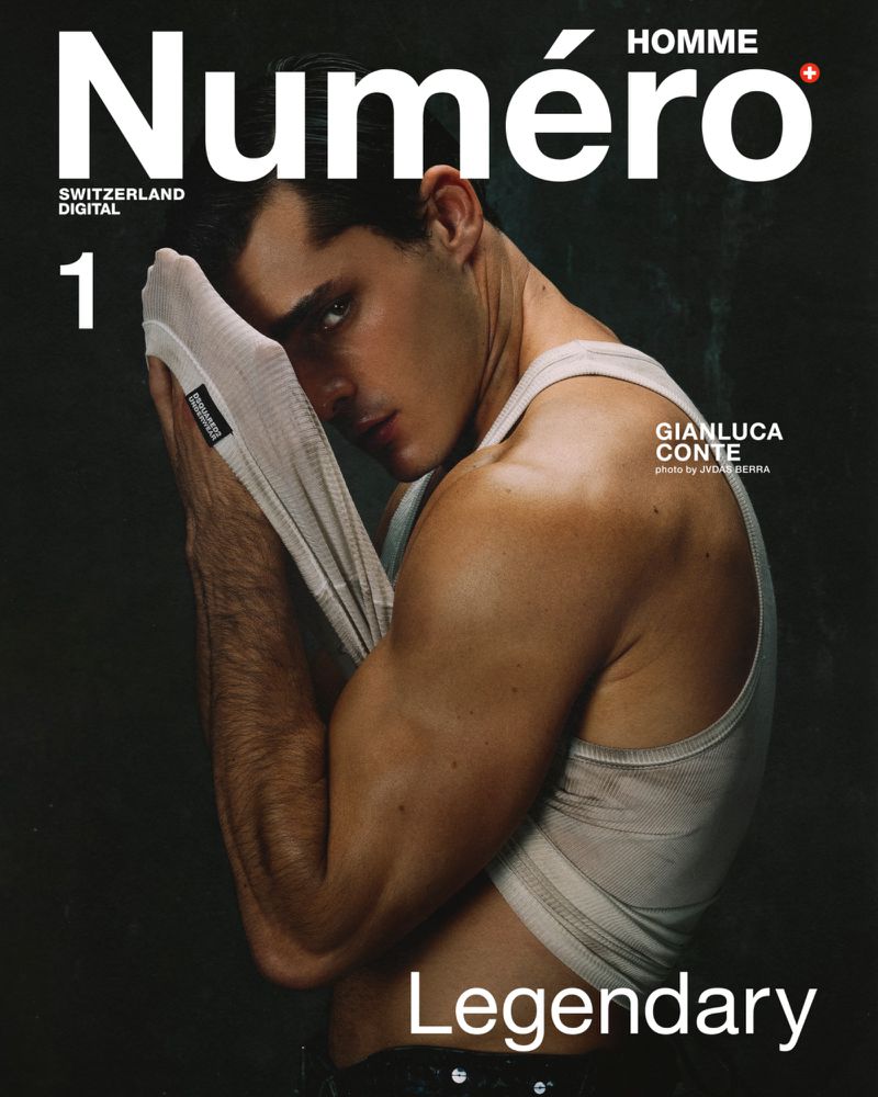 Man wearing a white ribbed tank top holding fabric against his face against a dark textured background