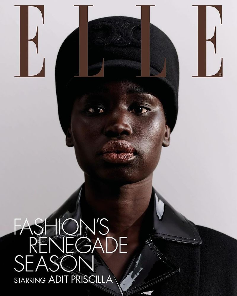 Elle magazine cover featuring Adit Priscilla. Close-up portrait of model wearing a black hat and coat against a light gray background.